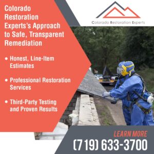 A restoration worker in a blue hazmat suit and yellow respirator carefully removes a piece of suspect material from a roof.